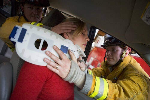 a fireman applying a neck brace to a woman after a car accident